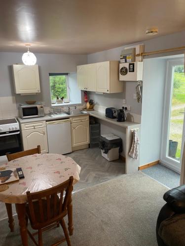 uma cozinha com armários brancos e uma mesa em Barfad Self Catering Holiday Cottages em Tarbert