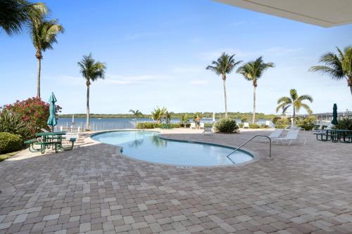 a swimming pool with palm trees and a body of water at Oceanfront Luxury Condo! Mins to beach! Rum Bar Next Door! in St. Petersburg
