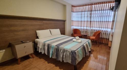 een slaapkamer met een bed, een tafel en een raam bij Lembranças Hotel in Huánuco