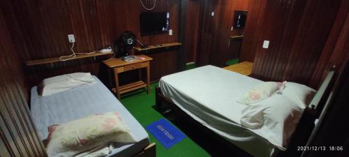 a room with two beds and a desk and a television at EL DORADO POUSADA in Barcelos