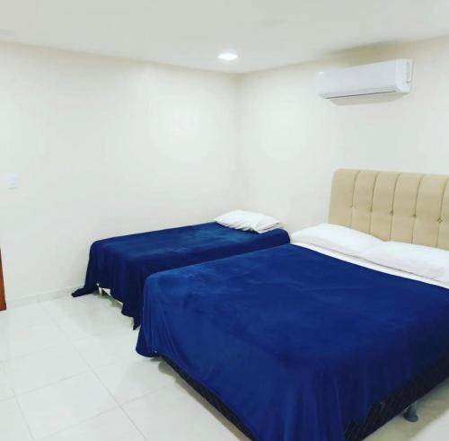 Duas camas num quarto branco com lençóis azuis em Atlântico Flat - Apto 004 em Natal