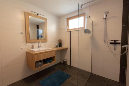 a bathroom with a sink and a mirror and a shower at Ferienwohnung Wallner in Wald am Arlberg