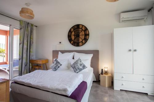 a bedroom with a bed and a clock on the wall at Hôtel Guadeloupe Palm Suites in Saint-François