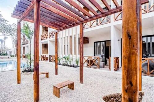 un pabellón con postes de madera y bancos frente a un edificio en Smart Depas Elegante apartamento estudio totalmente equipado, en Tulum