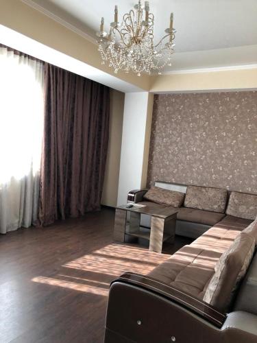 een woonkamer met een bank en een kroonluchter bij Квартира в центре Бишкека! in Bisjkek