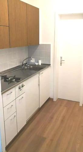 uma cozinha com armários brancos, um lavatório e um piso de madeira em Apartment Zentrum Bern Marzili em Berna