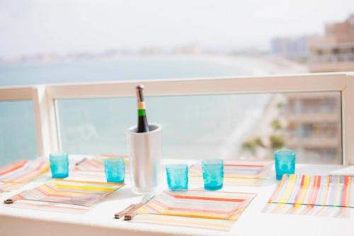 a table with a bottle of wine and blue glasses at Precioso apartamento en primera línea de playa in San Blas