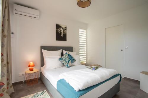 a bedroom with a bed and a table with a lamp at Hôtel Guadeloupe Palm Suites in Saint-François