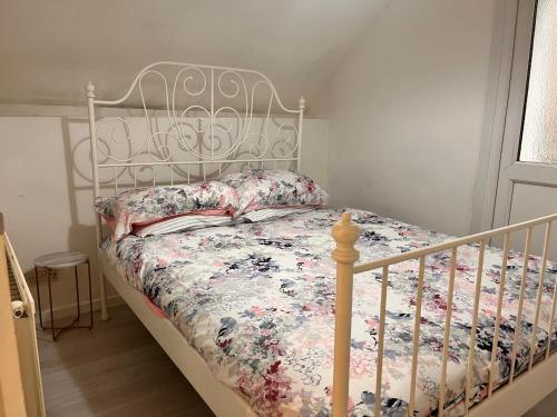 a white bed with a floral comforter in a bedroom at dyffryn cottage in Blaengawr