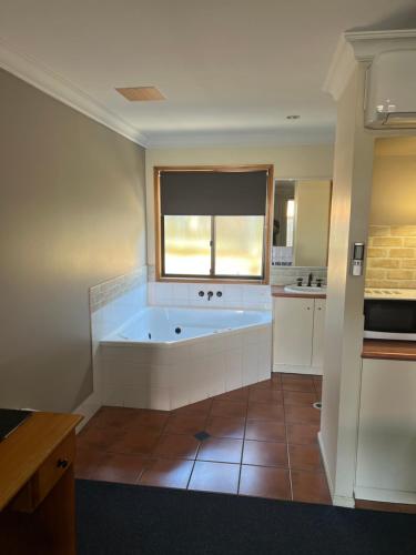 La grande salle de bains est pourvue d'une baignoire et d'une fenêtre. dans l'établissement Asters On James Motor Inn, à Toowoomba