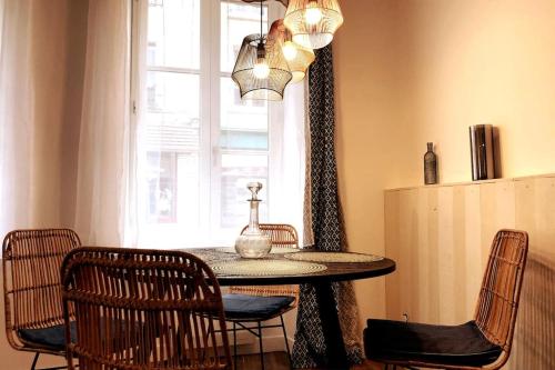 een eetkamer met een tafel met stoelen en een raam bij NATICOSY-Appartement centre historique avec jardin IDEAL COUPLE in Bellême