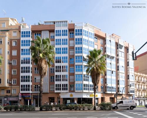 瓦倫西亞的住宿－Suites Rooms Valencia，一条街道前方有棕榈树的大建筑