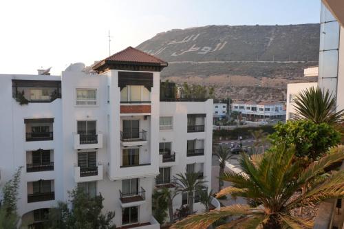 a white apartment building with a mountain in the background at mArinAr in Agadir