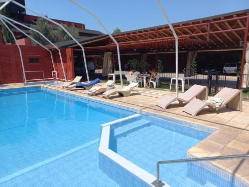 a swimming pool with lounge chairs next to a building at Colorina Complejo Residencial in San Rafael