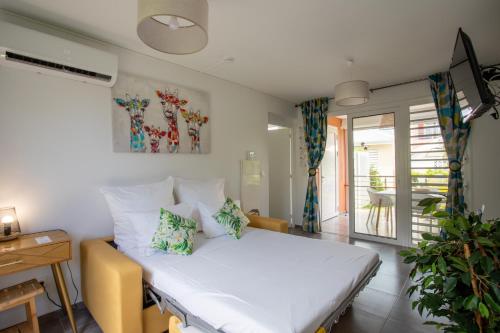 a bedroom with a bed and a desk and a table at Hôtel Guadeloupe Palm Suites in Saint-François