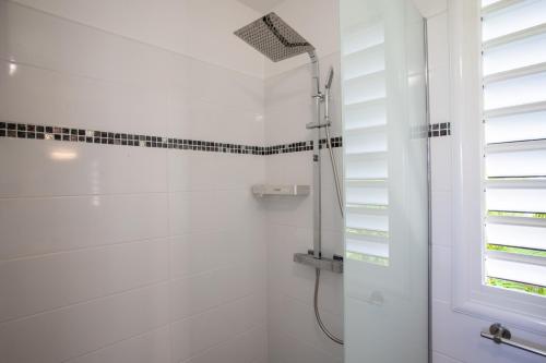 a white bathroom with a shower and a window at Hôtel Guadeloupe Palm Suites in Saint-François
