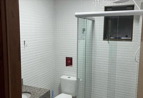 a bathroom with a toilet and a glass shower at Canto dos Pássaros Flat - Canasvieiras in Florianópolis