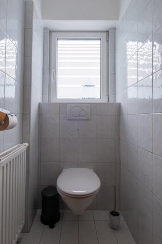 a white bathroom with a toilet and a window at Apart Leitner in Lermoos