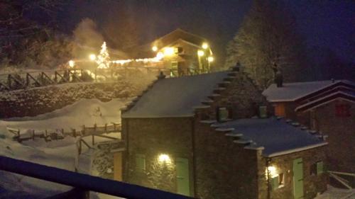 a house covered in snow at night with lights at Il Borgo Dei Celti in Fiumalbo