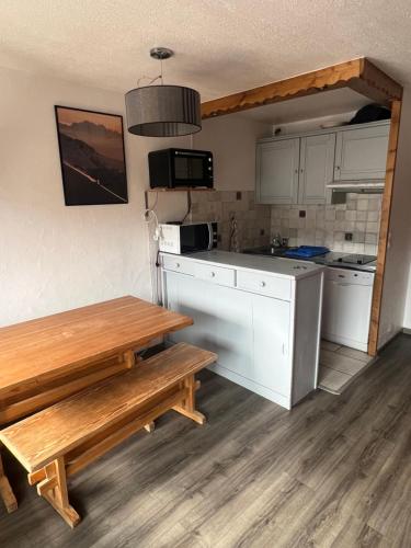 une cuisine avec des placards blancs, une table en bois et des bancs dans l'établissement Glaciers / 4 persons apartment, à Val Thorens