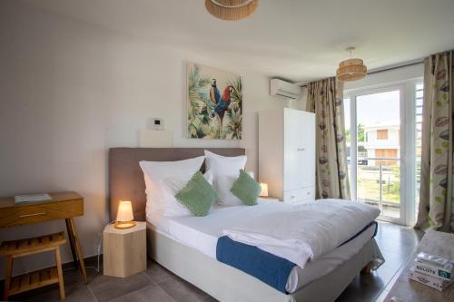 a bedroom with a bed with a lamp and a window at Hôtel Guadeloupe Palm Suites in Saint-François