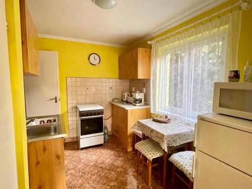 cocina con paredes amarillas, mesa y nevera en Napfény nyaraló en Orosháza