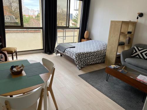 uma sala de estar com uma cama, um sofá e uma mesa em Le Studio Stanislas, calme et Lumière em Nancy