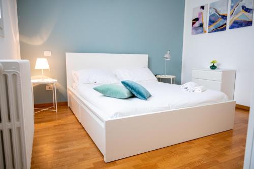 Trilocale zona Farini/Isola في ميلانو: سرير ابيض عليه وسادتين ازرق