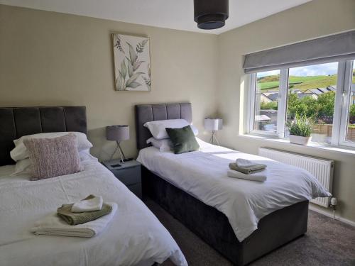 1 dormitorio con 2 camas y ventana en 'Benson View' - 2 bedroom Lake District home en Kendal