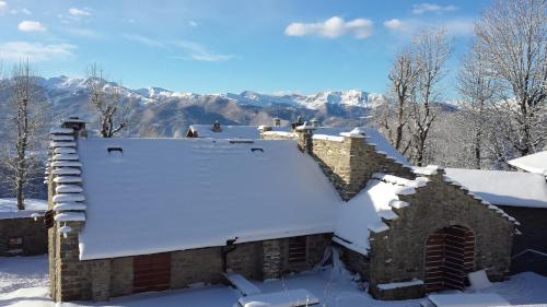 a building covered in snow with mountains in the background at Il Borgo Dei Celti in Fiumalbo