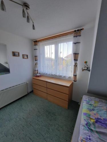 a bedroom with a bed and a window with a dresser at Ferienwohnung Gartenblick in Wildau