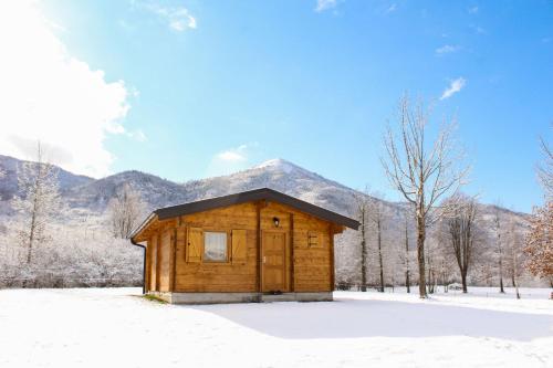 a wooden cabin in the snow with a mountain in the background at Vikendice Gornja Brezna - Mountain cabin Gornja Brezna in Plužine