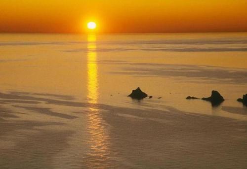 a sunset over the ocean with rocks in the water at Apartamentos Chinasol in Almuñécar