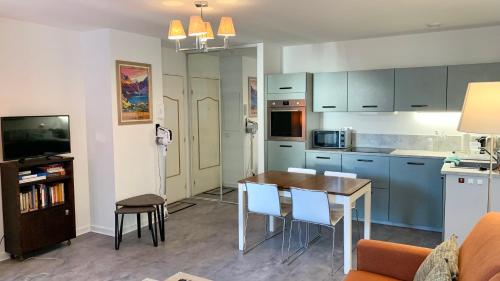 une cuisine avec une table et des chaises dans une pièce dans l'établissement Résidence Poste & Golf, appartement pour 4 personnes au cœur de Luchon, à Luchon