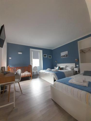 a blue bedroom with two beds and a desk at CA' DEL VINO Rooms- Varzo in Varzo