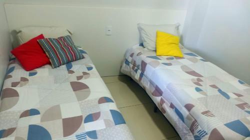 duas camas com almofadas coloridas sentadas uma ao lado da outra em Recanto Felicitá em Foz do Iguaçu