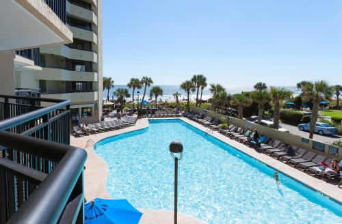 a swimming pool with chaise lounges and chairs at Ocean Reef Resort in Myrtle Beach