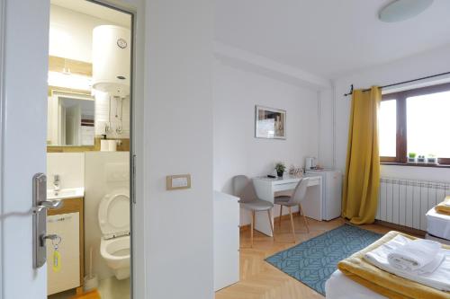 een badkamer met een wastafel, een toilet en een bureau bij AVIATOR APARTMENTS NIKOLA TESLA Belgrade in Surčin