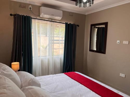 a bedroom with a bed and a window at Lukundo Place in Lusaka