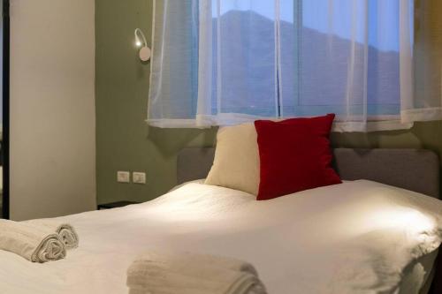 1 cama con almohada roja y ventana en family apartment Dead-sea view en Ovnat