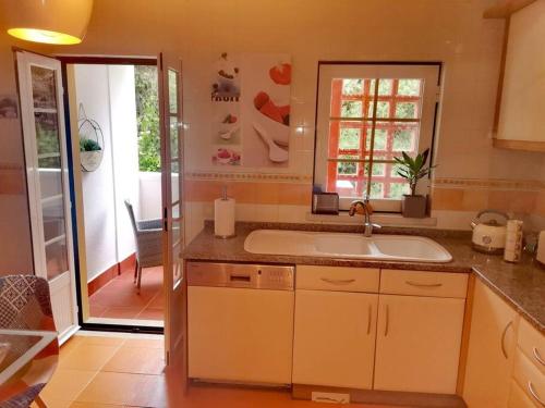a kitchen with a sink and a sliding glass door at Enjoy Beloura! in Sintra