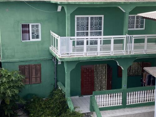a green house with a balcony on the side of it at Logement 2 chambres au sud de Mayotte in Bouéni