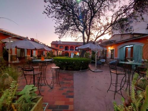 un patio al aire libre con sillas, mesas y sombrillas en Ñaupa House Hostel, en Cochabamba