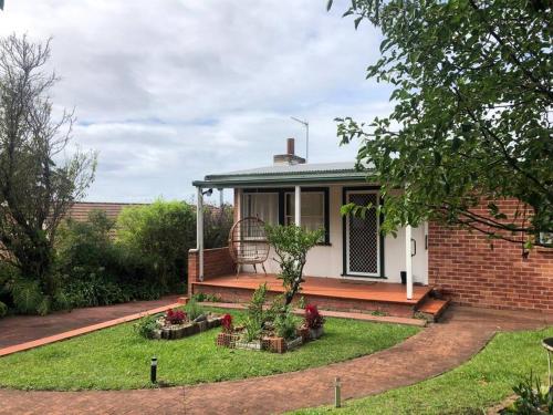 a brick house with a garden in front of it at Relaxing cottage overlooking Crookhaven River in Greenwell Point