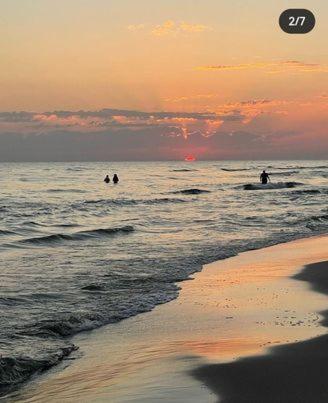 a group of people in the ocean at sunset at Apartament w Choczewie in Choczewo