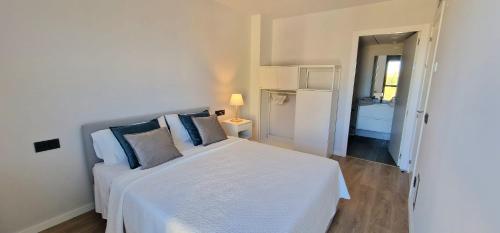 Dormitorio blanco con cama blanca y almohadas azules en Tina de Vila, en la capital del vino, en Vilafranca del Penedès