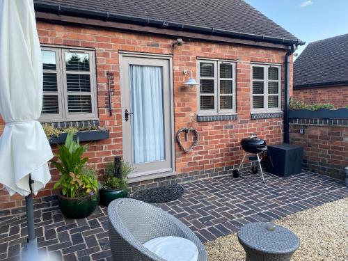a brick house with a patio with two chairs and a grill at The Snug with Jacuzzi -cosy hideout in Coventry