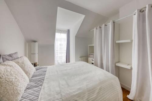 a white bedroom with a bed and a window at Le cosy in Saint-Cyr-lʼÉcole