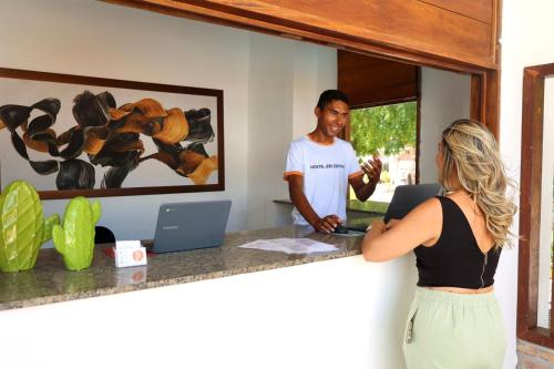 a man and a woman standing at a desk with a computer at Hostel Jeri Central in Jericoacoara