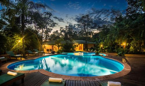 a swimming pool in a backyard at night at La Aldea De La Selva Lodge in Puerto Iguazú